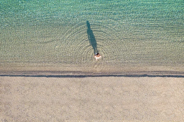 水着の若い運動選手の女性は海岸の砂のビーチで海に入る上で裸足で歩く 上からの眺め トップビュー コッパー — ストック写真