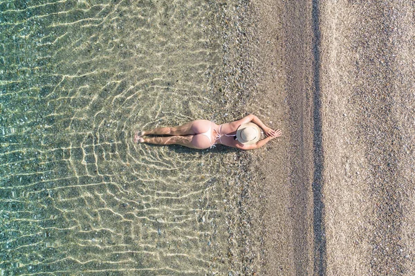 帽子の若い運動選手の女性は 水着を横にし 砂のビーチで海の水に日光浴 上からの眺め トップビュー コッパー — ストック写真