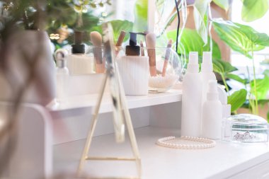 Makyaj aksesuarlarıyla birlikte makyaj masasının üzerindeki masa aynası. Kişisel bakım. Beyaz, pastel iç döşeme