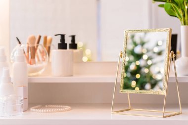 Noel ağacının yansıması, ampuller, makyaj malzemeleriyle makyaj masasındaki kadın aynası.