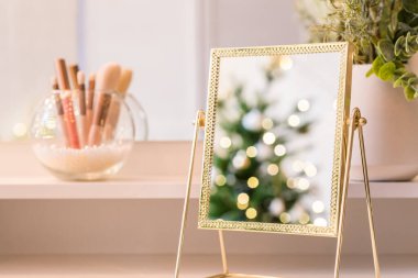 Noel ağacının yansıması, ampuller, makyaj malzemeleriyle makyaj masasındaki kadın aynası.