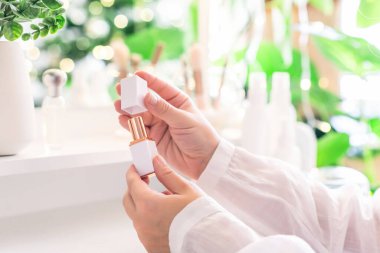 Makyaj aksesuarları ve masa aynasıyla makyaj masasının yanında oturan bir kadın. Beyaz iç mekan