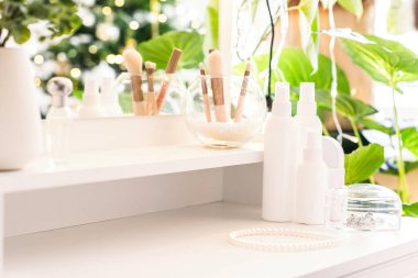 Günlük kadın kremi makyaj malzemeleriyle tuvalet masasında. Noel ağacının yansıması, masa aynasında ampuller..