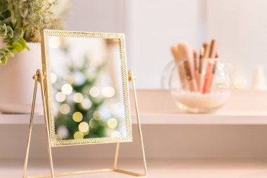 Noel ağacının yansıması, ampuller, makyaj malzemeleriyle makyaj masasındaki kadın aynası.