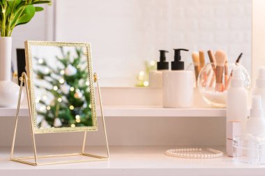 Noel ağacının yansıması, ampuller, makyaj malzemeleriyle makyaj masasındaki kadın aynası.