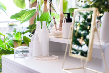 Noel ağacının yansıması, ampuller, makyaj malzemeleriyle makyaj masasındaki kadın aynası.