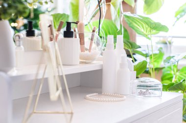 Makyaj aksesuarlarıyla birlikte makyaj masasının üzerindeki masa aynası. Kişisel bakım. Beyaz, pastel iç döşeme