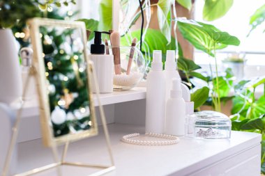 Noel ağacının yansıması, ampuller, makyaj malzemeleriyle makyaj masasındaki kadın aynası.