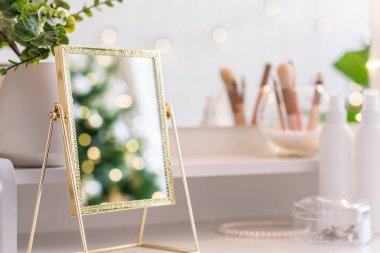 Noel ağacının yansıması, ampuller, makyaj malzemeleriyle makyaj masasındaki kadın aynası.