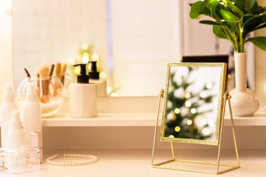 Noel ağacının yansıması, ampuller, makyaj malzemeleriyle makyaj masasındaki kadın aynası.