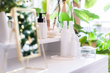 Noel ağacının yansıması, ampuller, makyaj malzemeleriyle makyaj masasındaki kadın aynası.