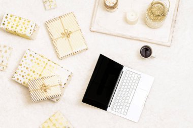 Noel zamanı. İnternetten alışveriş. Laptop, beyaz halıdaki beyaz altın ambalaj kağıdına sarılı hediyeler arasında. Üst Manzara. Kavram
