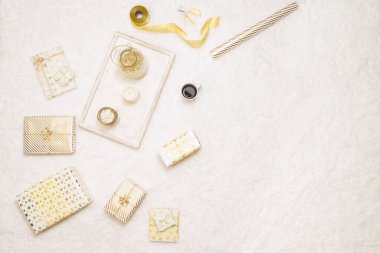 Aile için beyaz altın kağıtlara sarılı Noel hediyeleri kutuları. Tüylü kar beyazı halının üzerinde bir tepsi sıcak çikolata ve lokumla birlikte yatıyorlar. Uzayı kopyala Üst görünüm 