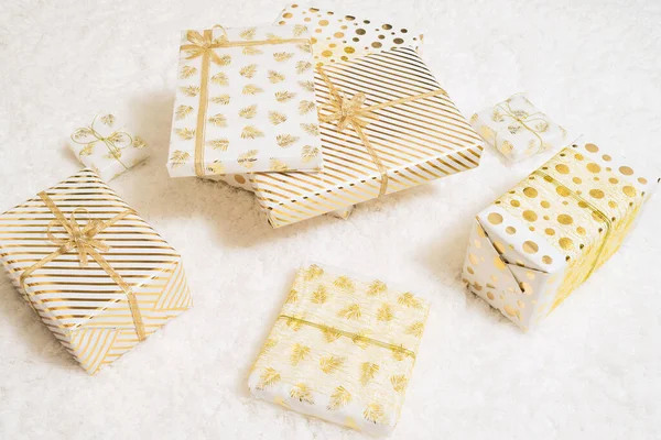 家族のための白い金の紙に包まれたクリスマスのギフトボックスは ふわふわの雪の白いカーペットに横たわっています トップ表示 — ストック写真