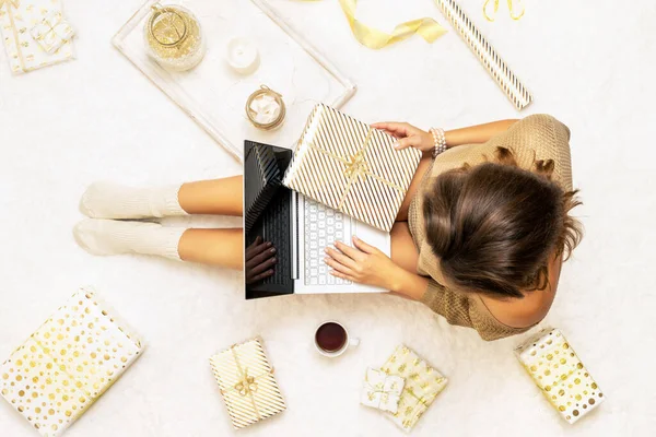 크리스마스 스웨터를 여성은 포장지로 포장된 상자들 사이에 아이디어를 노트북을 위에서 — 스톡 사진