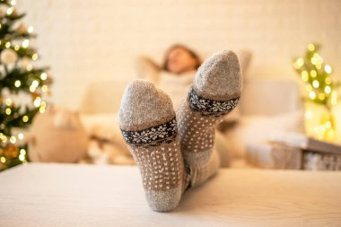 Noel ağacının yanındaki koltukta oturan kadın. Dişi bacaklar, kışın yün çoraplar, masaya koymak ve el yapımı hediye kutuları paketledikten sonra dinlenmek. Aile için hediyeler.