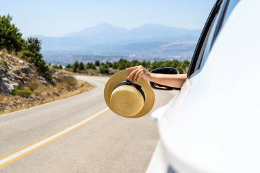Açık pencereden hasır şapka taşıyan bir kadın. Dağlardaki yılanlı yolda yolculuk. Yaz tatili