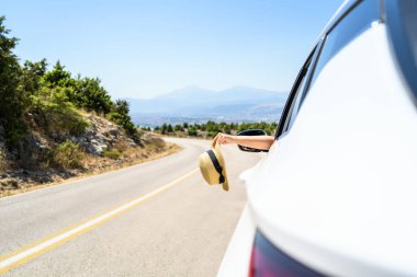 Açık pencereden hasır şapka taşıyan bir kadın. Dağlardaki yılanlı yolda yolculuk. Yaz tatili