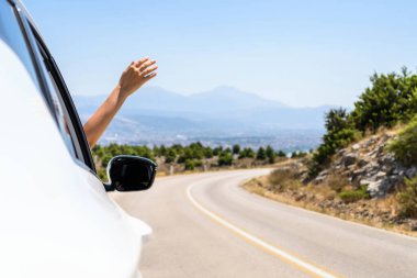 Pencereden elini uzatıp araba kullanan bir kadın. Dağlardaki yılanlı yolda yolculuk. Yaz tatili. Özgürlük kavramı. Boşluğu kopyala