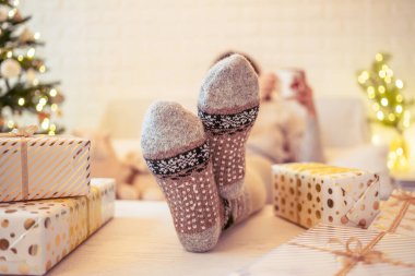 Odaklanamayan, bulanık bir kadın Noel ağacının yanında oturuyor ve aile için hediye paketlerini bitirdikten sonra bir fincan kakao ve şekerlemeyle rahatlıyor..