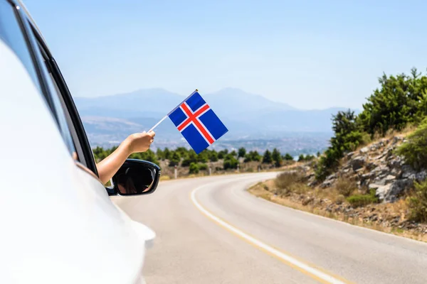 Kobieta Trzymająca Flagę Islandii Otwartego Okna Samochodu Jadąca Wzdłuż Drogi — Zdjęcie stockowe
