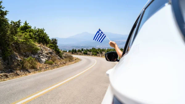 Kobieta Trzymająca Flagę Grecji Otwartego Okna Samochodu Jadącego Wzdłuż Drogi — Zdjęcie stockowe