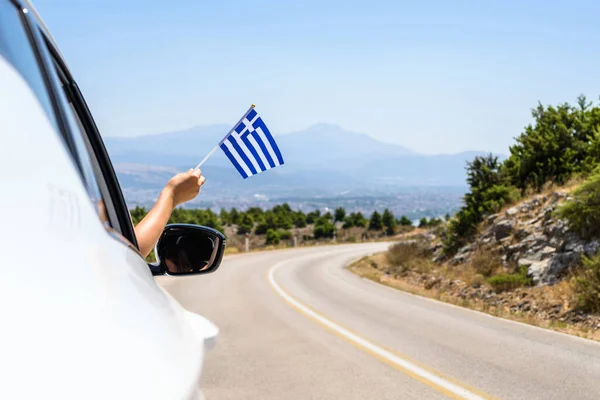 Kobieta Trzymająca Flagę Grecji Otwartego Okna Samochodu Jadącego Wzdłuż Drogi — Zdjęcie stockowe