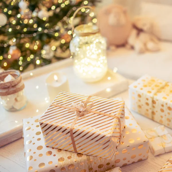 金色のライト 輝くガーランド キャンドルの真ん中にクリスマスツリーの近くのテーブルの上に横たわる手作りのギフトボックスを梱包することがたくさんあります 焦点を合わせて 正方形 — ストック写真