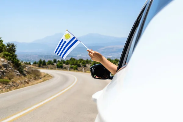 Kobieta Trzymająca Flagę Urugwaju Otwartego Okna Samochodu Jadąca Wzdłuż Drogi — Zdjęcie stockowe