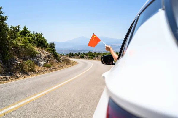 산속의 구불구불 한길을 운행하는 자동차 창문에서 국기를 — 스톡 사진