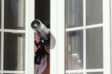 Gözetleme kameralı özel dedektif açık pencereden fotoğraf çekiyor. Kapatın. konsept.