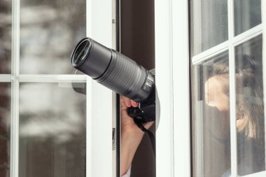 Gözetleme kameralı özel dedektif açık pencereden fotoğraf çekiyor. Kapatın. konsept.