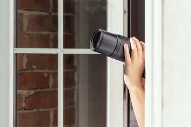 Gözetleme kameralı özel dedektif açık pencereden fotoğraf çekiyor. Kapatın. konsept.