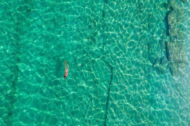 Alone naked nudist man dives in flippers, snorkeling mask and tube swimming in sea, ocean turquoise clear water. Top view. Aerial, drone, copter view.