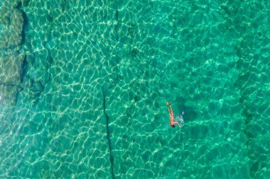 Alone naked nudist man dives in flippers, snorkeling mask and tube swimming in sea, ocean turquoise clear water. Top view. Aerial, drone, copter view.