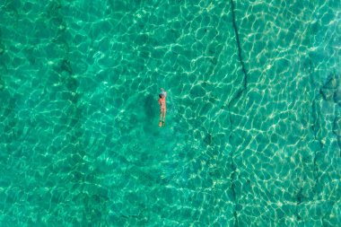 Alone naked nudist man dives in flippers, snorkeling mask and tube swimming in sea, ocean turquoise clear water. Top view. Aerial, drone, copter view.