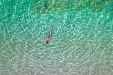 Top, aerial view. Young beautiful woman in a red bikini panties swimming in sea water on the sand beach. Drone, copter photo. Summer vacation. View from above. 