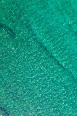Background, texture of relaxing, calm turquoise, transparent sea water with stones, slabs, lump, coral. Summer vacation. Blue ocean lagoon. Drone, copter top view. 