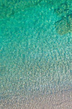 Background, texture of relaxing, calm turquoise, transparent sea water with stones, slabs, lump, coral. Summer vacation. Blue ocean lagoon. Drone, copter top view. 