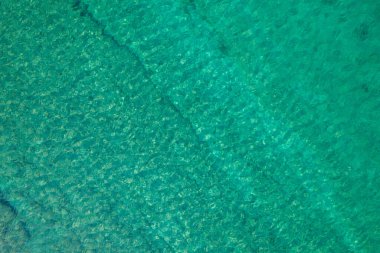 Background, texture of relaxing, calm turquoise, transparent sea water with stones, slabs, lump, coral. Summer vacation. Blue ocean lagoon. Drone, copter top view. 