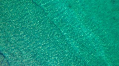 Background, texture of relaxing, calm turquoise, transparent sea water with stones, slabs, lump, coral. Summer vacation. Blue ocean lagoon. Drone, copter top view. 