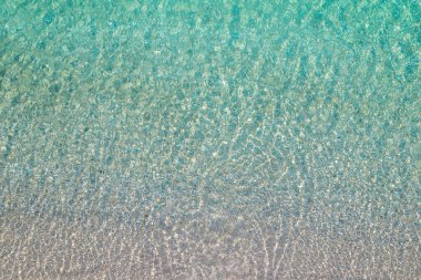 Background, texture of relaxing, calm turquoise, transparent sea water with stones. Summer vacation. Blue ocean lagoon. Drone, copter top view. 
