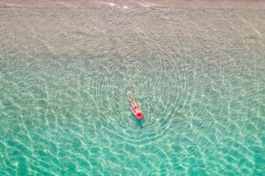 Üst Manzara. Kumsalda deniz suyunda yüzen kırmızı şapkalı ve bikinili güzel bir kadın. Drone, helikopter fotoğrafı. Yaz tatili. Yukarıdan görüntüle. 
