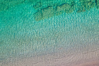 Background, texture of relaxing, calm turquoise, transparent sea water with stones, slabs, lump, coral. Summer vacation. Blue ocean lagoon. Drone, copter top view. 