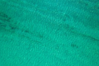Background, texture of relaxing, calm turquoise, transparent sea water with stones, slabs, lump, coral. Summer vacation. Blue ocean lagoon. Drone, copter top view. 