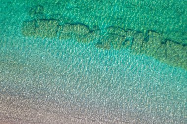 Background, texture of relaxing, calm turquoise, transparent sea water with stones, slabs, lump, coral. Summer vacation. Blue ocean lagoon. Drone, copter top view. 