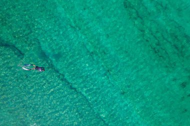 Spearfishing scuba diver in tropical exotic sea, ocean turquoise clear water. Man swimming hunting exotic fish, poaching. Top view. Aerial, drone, copter view.