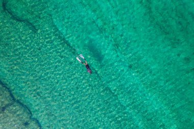Spearfishing scuba diver in tropical exotic sea, ocean turquoise clear water. Man swimming hunting exotic fish, poaching. Top view. Aerial, drone, copter view.