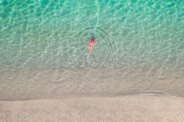 Üst Manzara. Kumsalda deniz suyunda yüzen kırmızı şapkalı ve bikinili güzel bir kadın. Drone, helikopter fotoğrafı. Yaz tatili. Yukarıdan görüntüle. 