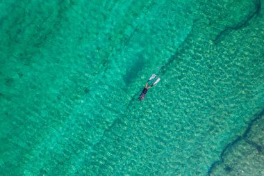 Spearfishing scuba diver in tropical exotic sea, ocean turquoise clear water. Man swimming hunting exotic fish, poaching. Top view. Aerial, drone, copter view.